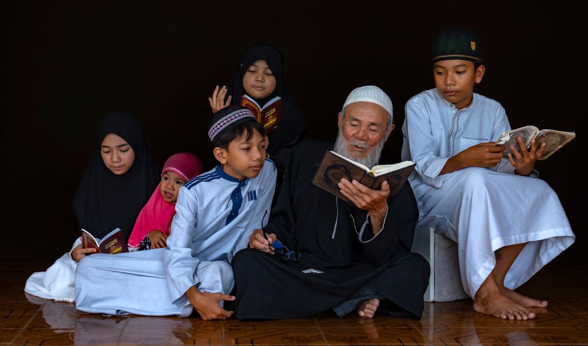 A grandfather reading the Qur'an together with his grandchildren